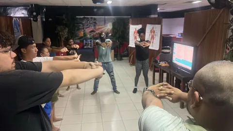 De hele groep doet rek- en strekoefeningen in het leslokaal, met anatomieposters aan de wand
