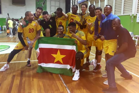 Een Surinaams handbalteam viert met de vlag na de wedstrijd